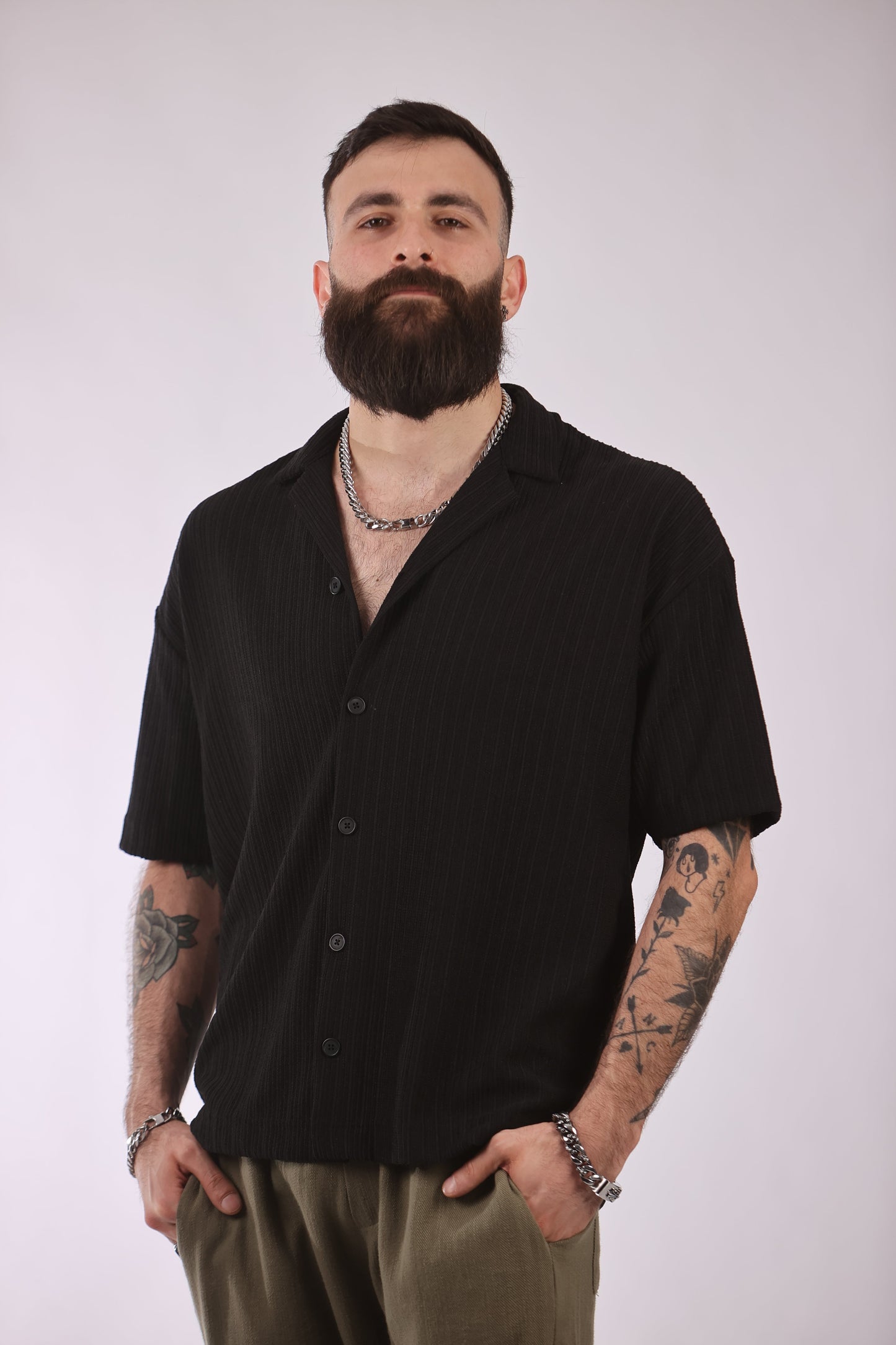 Marrakech shirt with black short sleeves, worn by a person with tattoos.