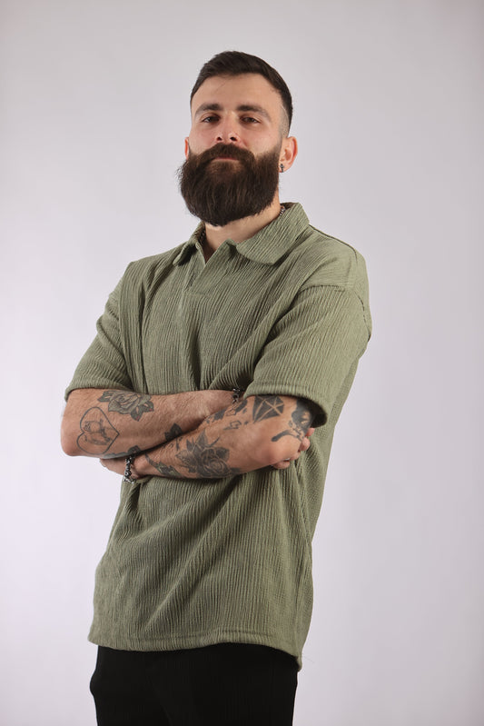 Marrakech polo shirt in green, durable 100% polyester fabric with moisture-wicking properties, worn by tattooed man.