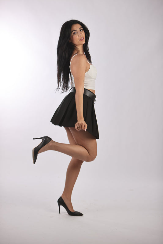 Quzu pleated skirt with removable belt in black, worn by a woman in heels.
